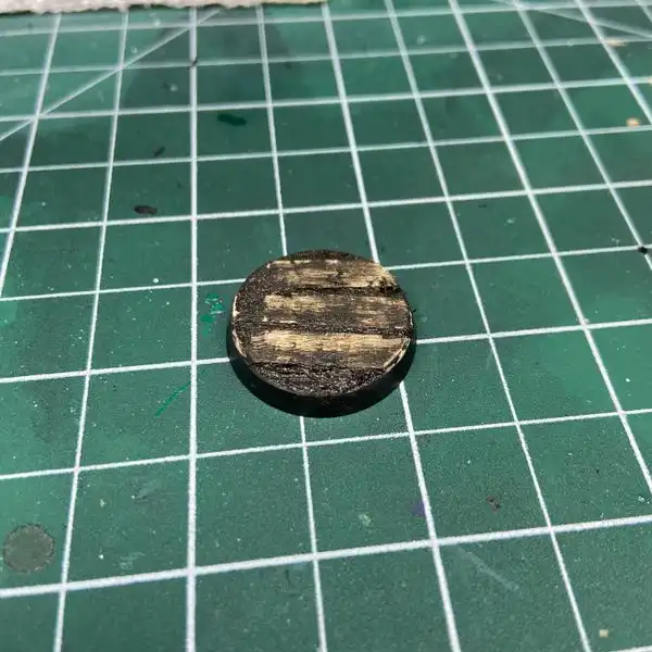 Muddy Warhammer base on top of a hobby cutting mat